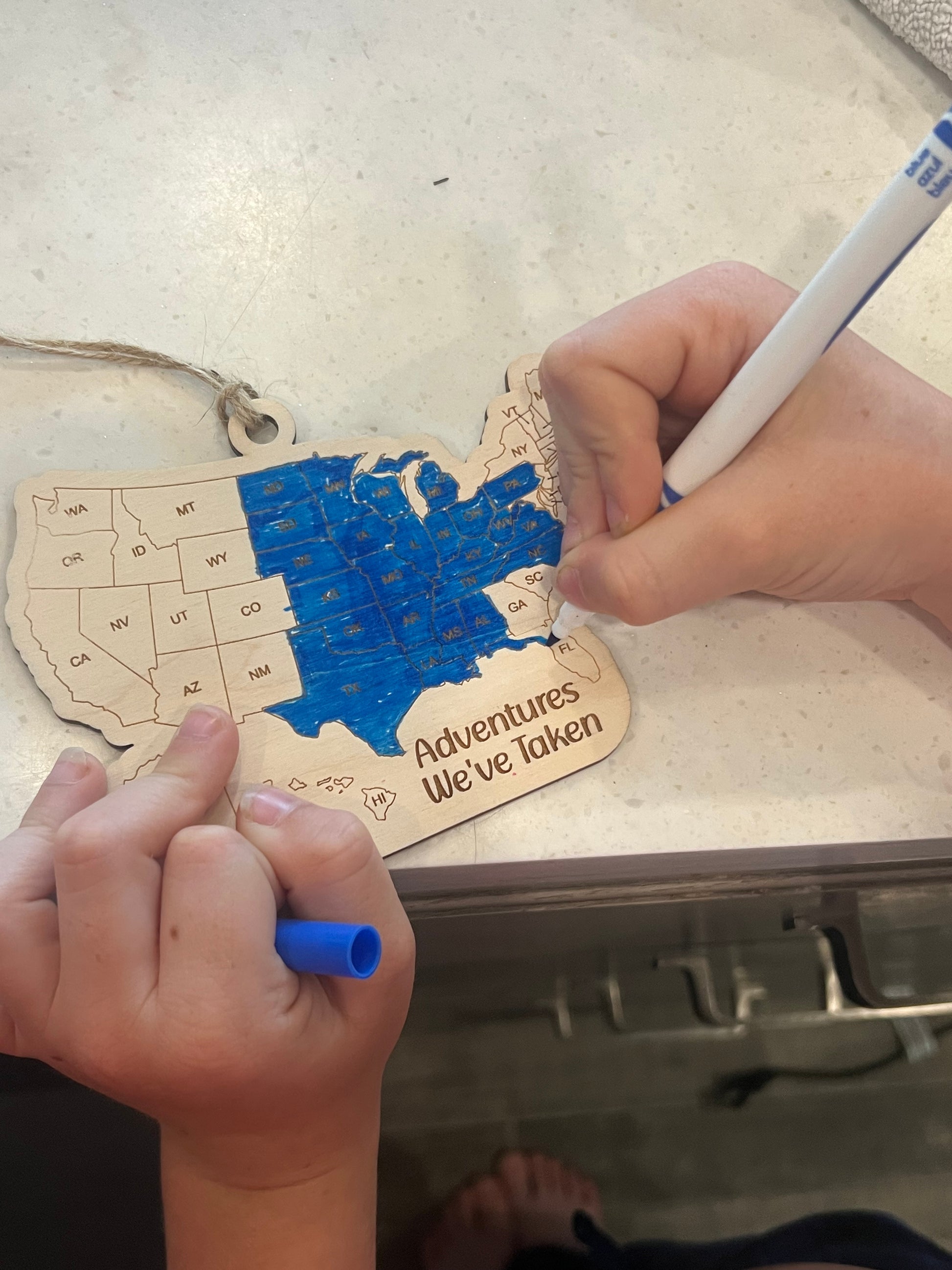 Person coloring a wooden map of the United States with markers
