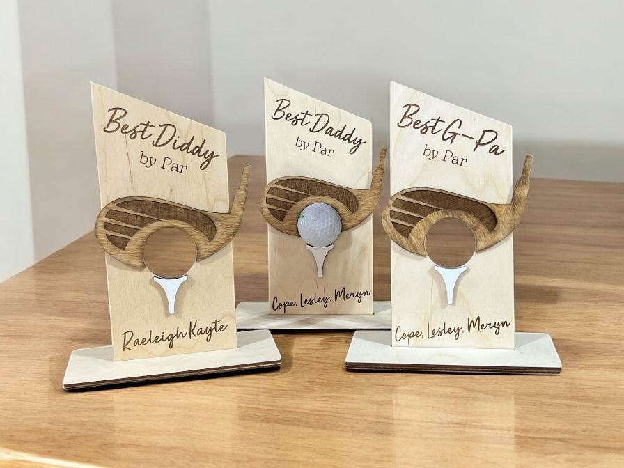 Three wooden plaques with golf-themed designs on a wooden surface.