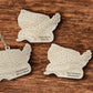 Three US map-shaped wooden ornaments on a wooden surface