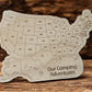 Wooden map of the United States with 'Our Camping Adventures' text on a wooden surface.