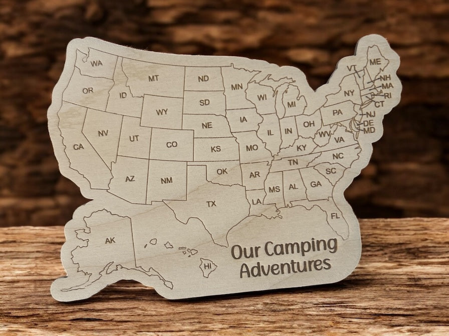 Wooden map of the United States with 'Our Camping Adventures' text on a wooden surface.