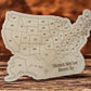 Wooden cutout of the United States with 'States We've Been To' text on a wooden surface