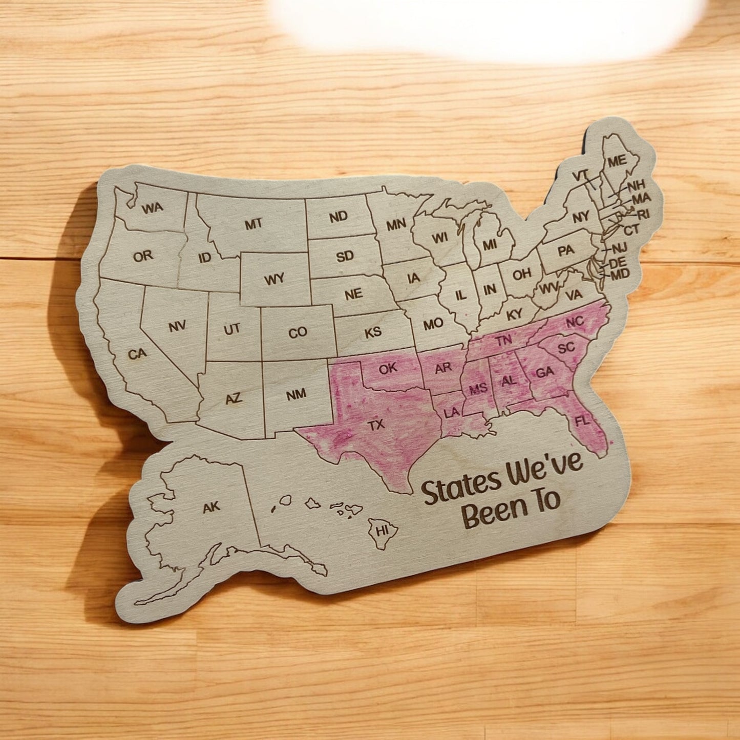 Wooden map of the United States with 'States We've Been To' text on a wooden surface