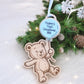 Decorative ornament with teddy bear design and 'Hogan's First Christmas 2025' text on a Christmas tree.